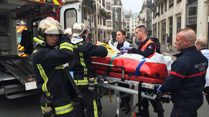 Firefighters carry an injured man on a stretcher in front of the offices of the French satirical newspaper Charlie Hebdo in Paris on January 7, 2015.(AFP Photo / Philippe Dupeyrat)