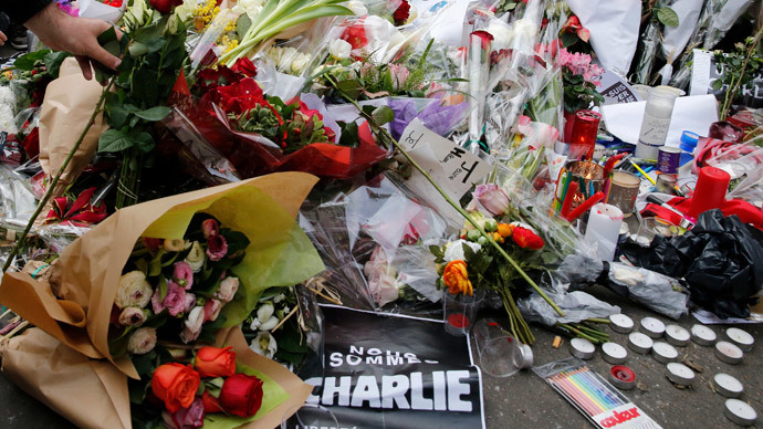 A man places a rose as people continue to pay tribute in front of the offices of the weekly satirical newspaper Charlie Hebdo in Paris January 10, 2015.(Reuters / Pascal Rossignol)