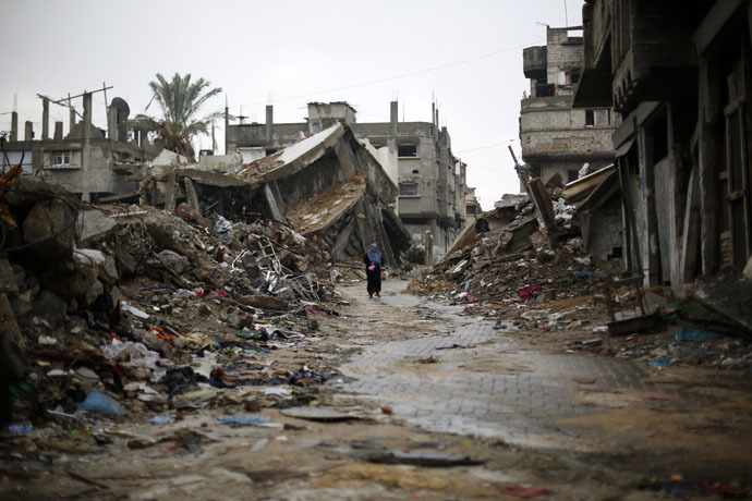 A Palestinian woman walks in the rain past houses that were destroyed during the 50-day Gaza war between Israel and Hamas-led militants (AFP Photo)