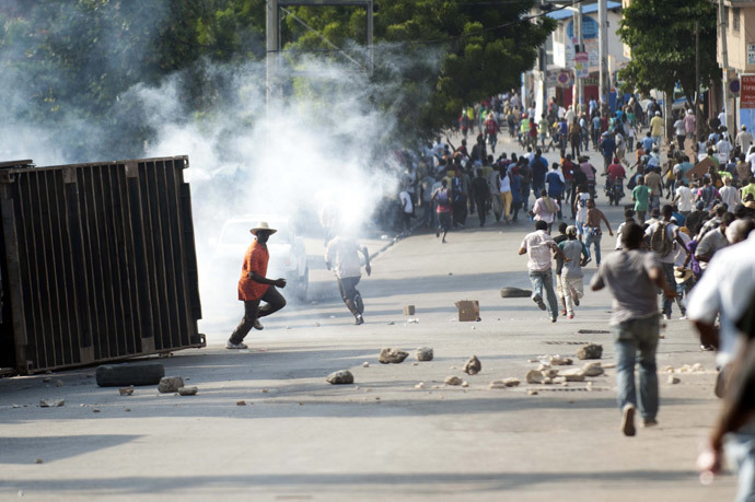 Protesters flee tear gas fired by Haitian Police during clashes in a march against the government of Haitian President Michel Martelly in Port-au-Prince on January 17, 2015. (AFP Photo / Hector Retamal)