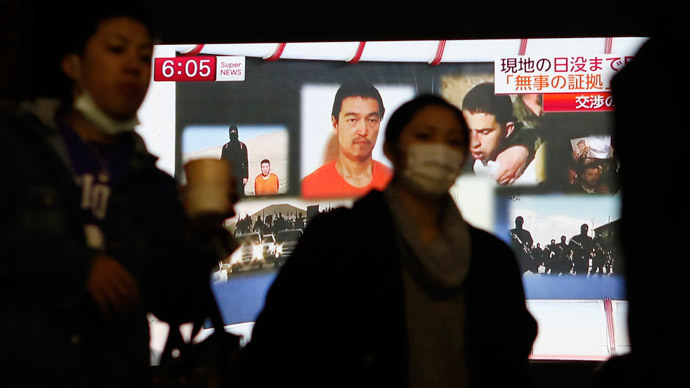 People walk past a TV screen broadcasting a news program about Islamic State hostages Jordanian air force pilot Muath al-Kasaesbeh (back top 3rd L) and Japanese journalist Kenji Goto (back top 2nd L), along a street in Tokyo January 29, 2015.(Reuters / Yuya Shino)