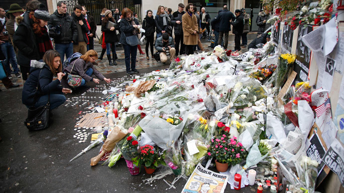 Citizens surround flowers placed near the offices of weekly satirical newspaper Charlie Hebdo in Paris January 9, 2015.(Reuters / Charles Platiau)