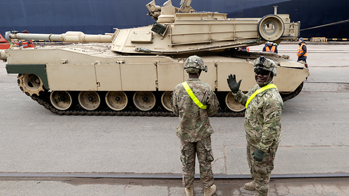 A U.S. soldier greets the media as custom officers inspect an Abrams main battle tank, for U.S. troops deployed in the Baltics as part of NATO's Operation Atlantic Resolve, at Riga port March 9, 2015 (Reuters / Ints Kalnins)