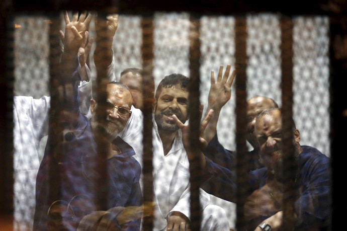 Muslim Brotherhood's senior member Mohamed El-Beltagy (R) and deputy head of the Freedom and Justice Party Essam El-Erian (L) gesture the four-finger Rabia sign from behind bars with other Muslim Brotherhood members at a court in the outskirts of Cairo, April 21, 2015. (Reuters/Amr Abdallah Dalsh)