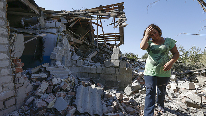 A woman walks at her destroyed house in the village of Kominternovo, on the outskirts of the southern coastal town of Mariupol (Reuters / Vasily Fedosenko)