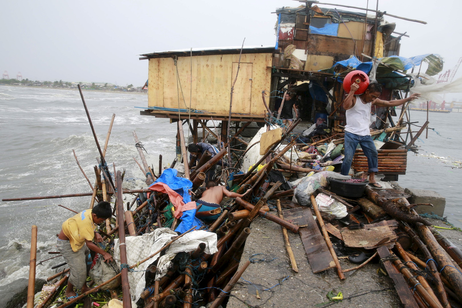 Une famille cherche le long de la côte de la baie de Manille des biens récupérables après la destruction de leur maison