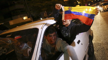 Des partisans de l'opposition vénézuélienne brandissent un drapeau national a Caracas en fêtant la première victoire de l'opposition aux élections parlementaires depuis 16 ans.
