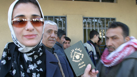 Une femme montre son nouveau passeport irakien devant un bâtiment officiel.