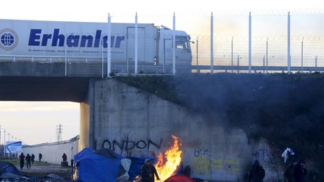 Les migrants se réchauffent les mains à côté d’un feu de bois près du camp de la «Jungle», à Calais, dans le Nord de la France