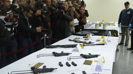 Un membre du BCIJ montre les armes saisies aux groupes terroristes au cours d'une conférence de presse le 19 février