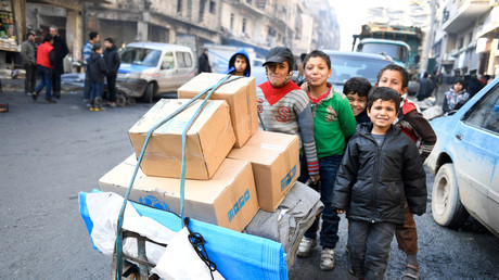 Des enfants poussent un chariot d'aide humanitaire dans les rues d'Alep-est.