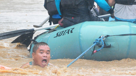 Un homme s'accroche à une corde attachée à un canot de sauvetage, alors que les habitants de la ville de Cagayan de Oro, aux Philippines, sont évacués, le 22 décembre.