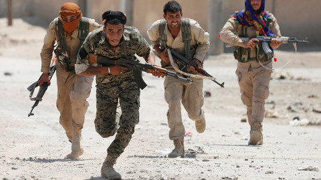Des combattants kurdes des Unités de protection du peuple (YPG) traversent une rue à Raqqa, en Syrie, le 3 juillet 2017.