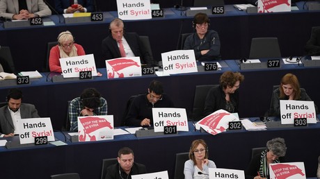 Des députés européens montrent des affiches «Bas les pattes de la Syrie» lors de l'allocution du président français Emmanuel Macron le 17 avril 2018 à Bruxelles. 