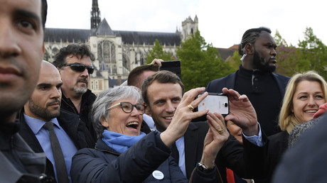 Candidat à l'élection présidentielle, Emmanuel Macron pose pour un «selfie» avec une partisane à l'extérieur de la cathédrale d'Amiens le 26 avril 2017, tandis que son garde du corps, surnommé Makao, monte la garde derrière eux.