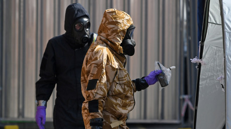 Un enquêteur portant une tenue de protection camouflée, des gants et un masque à gaz travaille avec un enquêteur de la police à Amesbury, au sud de l'Angleterre, le 6 juillet 2018