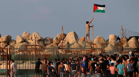 Un manifestant brandit un drapeau palestinien en franchissant la barrière israélienne lors d'une manifestation à la frontière maritime avec Israël, dans le nord de la bande de Gaza, le 8 octobre 2018.