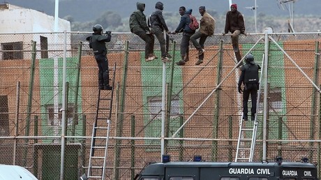 Des policiers espagnols venant chercher des migrants assis sur la clôture à la frontière de Melilla, en 2015. 