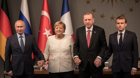 Angela Merkel, Vladimir Poutine, Recep Tayyip Erdogan et Emmanuel Macron se tiennent la main lors du sommet d'Istanbul, le 27 octobre 2018. 