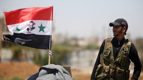 Un militaire se tient près d'un drapeau syrien à Deraa (image d'illustration).