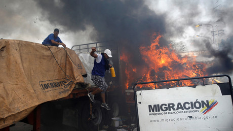 Des partisans de l'opposition déchargent de l'aide humanitaire d'un camion incendié après des affrontements entre les partisans de l'opposition et les forces de sécurité vénézuéliennes sur le pont Francisco de Paula Santander, le long de la frontière entre la Colombie et le Venezuela.