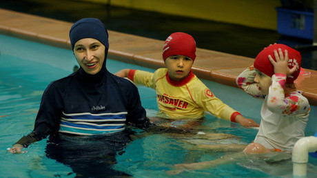 Une femme en burkini entourée d'enfants dans une piscine (image d'illustration).