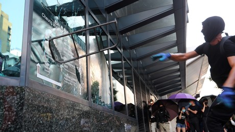 Un manifestant casse la vitre d'un bâtiment gouvernemental lors d'une manifestation à Hong Kong le 1er octobre.