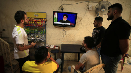 Des jeunes gens regardent le chef du Hezbollah libanais Sayyed Hassan Nasrallah lors de son discours diffusé à la télévision depuis un café situé dans la ville portuaire de Sidon, au Liban, le 25 octobre 2019.