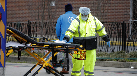 Un ambulancier pulvérise du désinfectant sur une civière à l'extérieur du Brooklyn Hospital Center pendant l’épidémie de Covid-19 dans le quartier de Brooklyn à New York, le 31 mars 2020.
