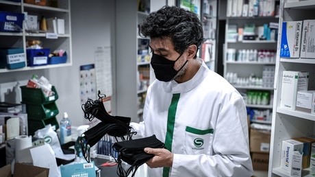 Un pharmacien portant un masque protecteur, montre les masques lavables et en tissu vendus dans une pharmacie à Paris, le 29 avril 2020 (image d'illustration).