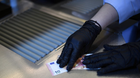 Un billet de 10 euros manipulé avec des gants de protection en pleine pandémie du Covid-19.