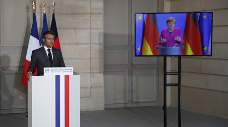 Le président français Emmanuel Macron écoute la chancelière allemande Angela Merkel depuis le palais de l’Elysée à Paris à  l’occasion d'une conférence de presse vidéo conjointe, le 18 mai 2020.