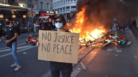 Un manifestant brandit une pancarte «Pas de justice, pas de paix», devant un feu.