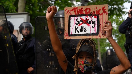 Une manifestante tient une pancarte «The police kills [la police tue]» devant les forces de l'ordre à Marseille, le 6 juin 2020.