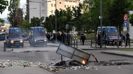 Des gendarmes se tiennent près de leurs véhicules alors que des ordures brûlent dans une rue du quartier des Gresilles à Dijon, le 15 juin 2020.