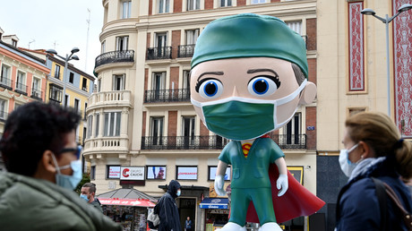 Des personnes portant des masques marchent le 24 septembre 2020 près d'une statue de 6 mètres de haut représentant un «Superhealthworker», installée à Madrid pour rendre hommage aux «héros» qui luttent contre le coronavirus (image d'illustration).