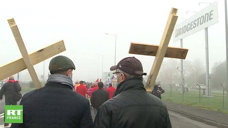 Des salariés de l'usine Bridgestone portent des croix en bois sur lesquelles ils ont inscrit leurs matricules