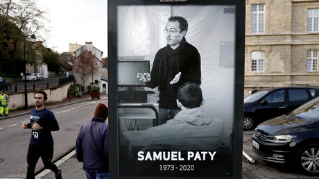 Des piétons passent devant une affiche représentant le professeur de français Samuel Paty à Conflans-Sainte-Honorine, le 3 novembre 2020,