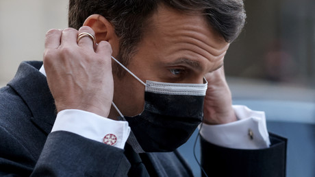 Le président français Emmanuel Macron enfile son masque à l'Elysee le 23 mars 2021.