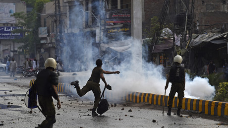 Un policier jette une pierre en direction des partisans de Tehreek-e-Labbaik Pakistan (TLP) lors d'une manifestation à Lahore le 12 avril 2021, après l'arrestation de leur chef, qui a appelé à l'expulsion de l'ambassadeur de France.
