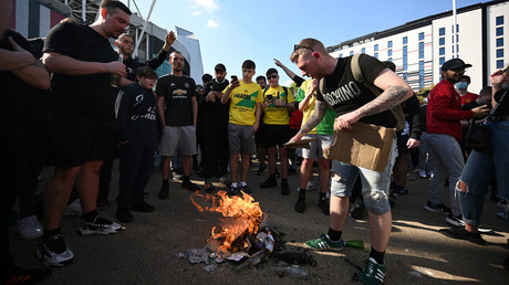 Des supporters de Manchester United brûlent un drapeau américain en opposition aux patrons du club