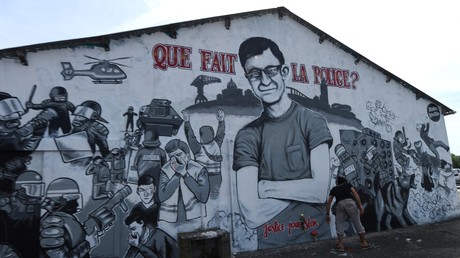 Une femme marche devant une freque murale représentant un portrait de Steve Maia Canico le 3 août 2019, à Nantes.