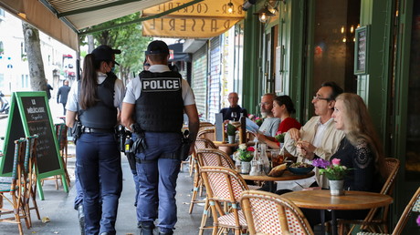 Des policiers français patrouillent devant un restaurant pour vérifier la conformité de l'application du pass sanitaire à Paris le 18 août 2021.
