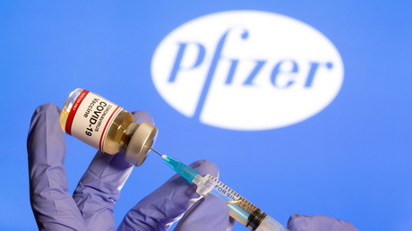 Un flacon et une seringue médicale devant le logo Pfizer (image d'illustration).