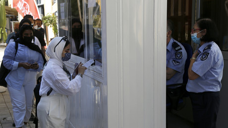 A Nicosie, une femme portant un masque montre son test Covid à un policier
