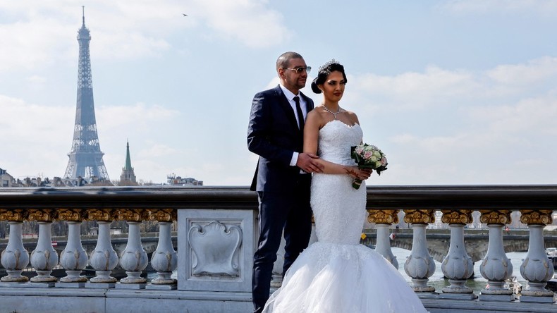 Un couple de jeunes mariés pose pour une séance photo sur le pont Alexandre III à Paris le 20 mars 2021.