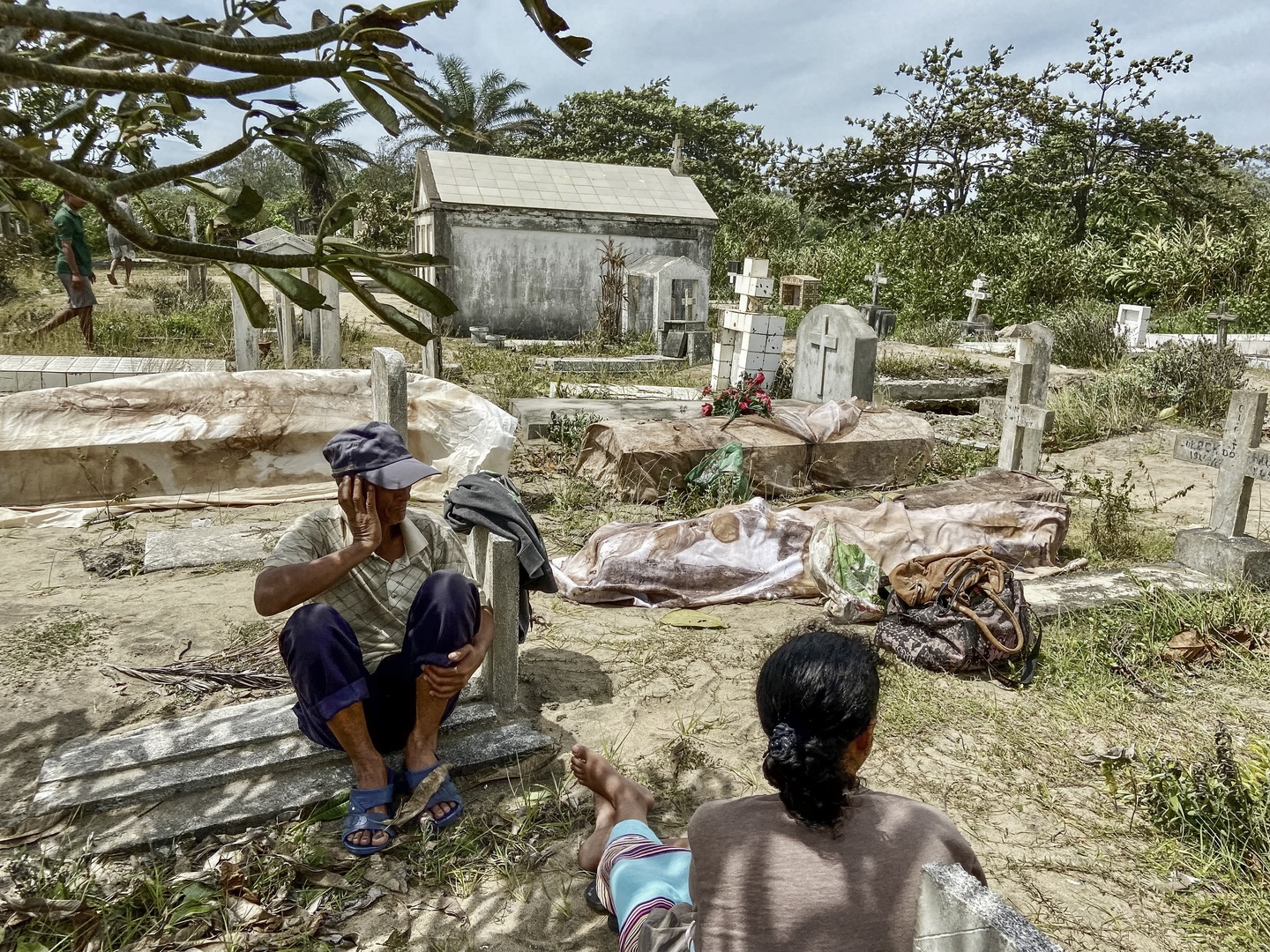 Des proches sont assis à côté de corps exhumés de tombes détruites par le cyclone Batsirai au cimetière local de Mahanoro le 6 février 2022.