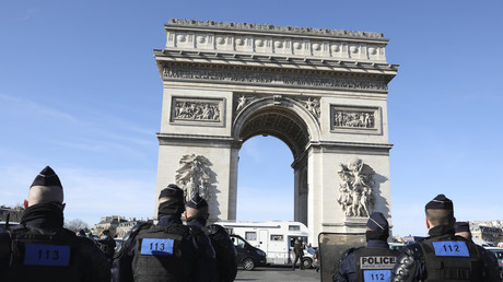 Un camping-car faisant partie d'un convoi passe devant l'Arc de Triomphe sur l'avenue des Champs-Elysées alors que des policiers montent la garde, le 12 février 2022 à Paris (image d'illustration).