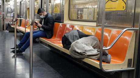 Un homme dort sur les sièges du métro de New York