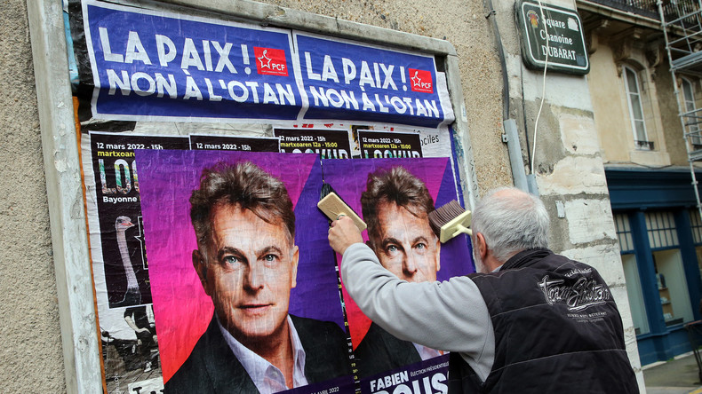 Un militant communiste placarde des affiches en faveur de Fabien Roussel